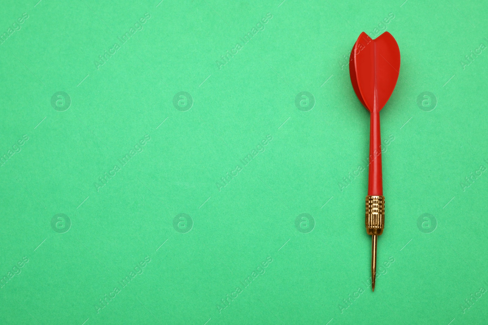 Photo of Red dart arrow on green background, top view with space for text