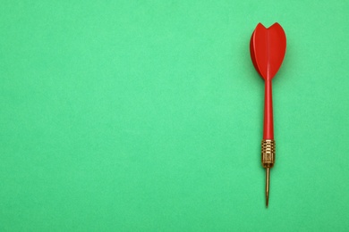 Photo of Red dart arrow on green background, top view with space for text