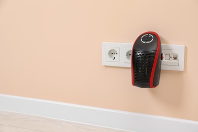 Photo of Modern compact electric heater charging from socket indoors, space for text