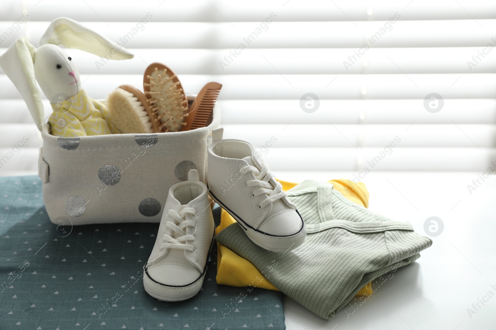 Photo of Baby clothes, shoes and accessories near window indoors