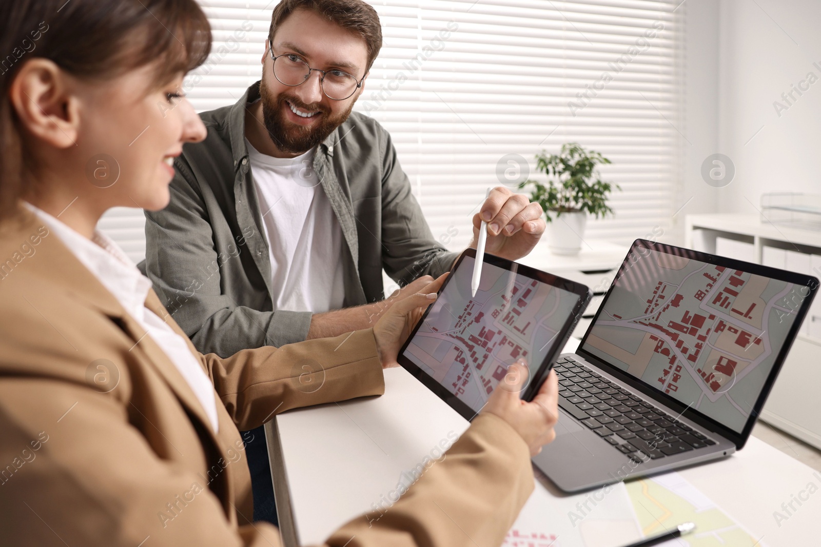 Photo of Cartographers working with cadastral map on tablet at white table in office