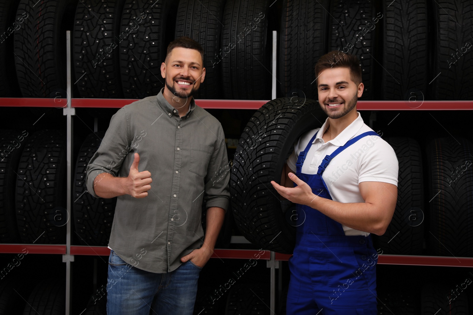 Photo of Mechanic helping client to choose car tire in auto store