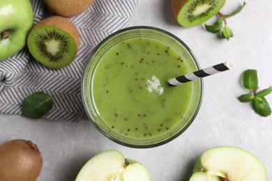 Photo of Delicious kiwi smoothie and fresh fruits on light grey table, flat lay