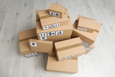 Photo of Cardboard boxes with different packaging symbols on floor, above view. Parcel delivery