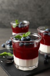 Photo of Delicious panna cotta with fruit coulis and fresh blueberries served on grey table