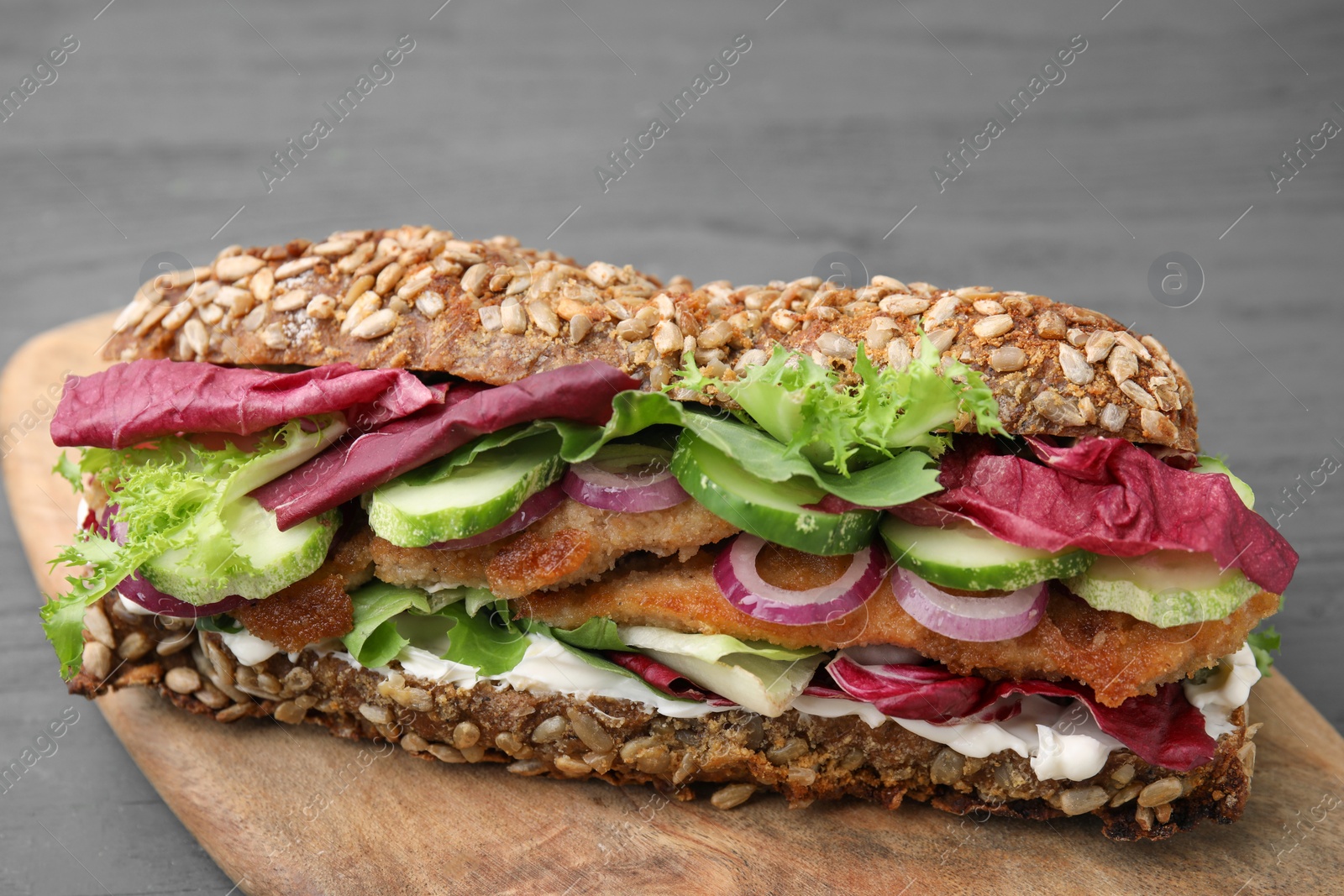 Photo of Delicious sandwich with schnitzel on dark wooden table, closeup