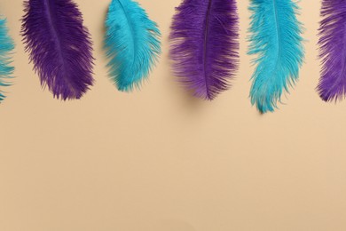 Photo of Beautiful violet and light blue feathers on beige background, flat lay. Space for text