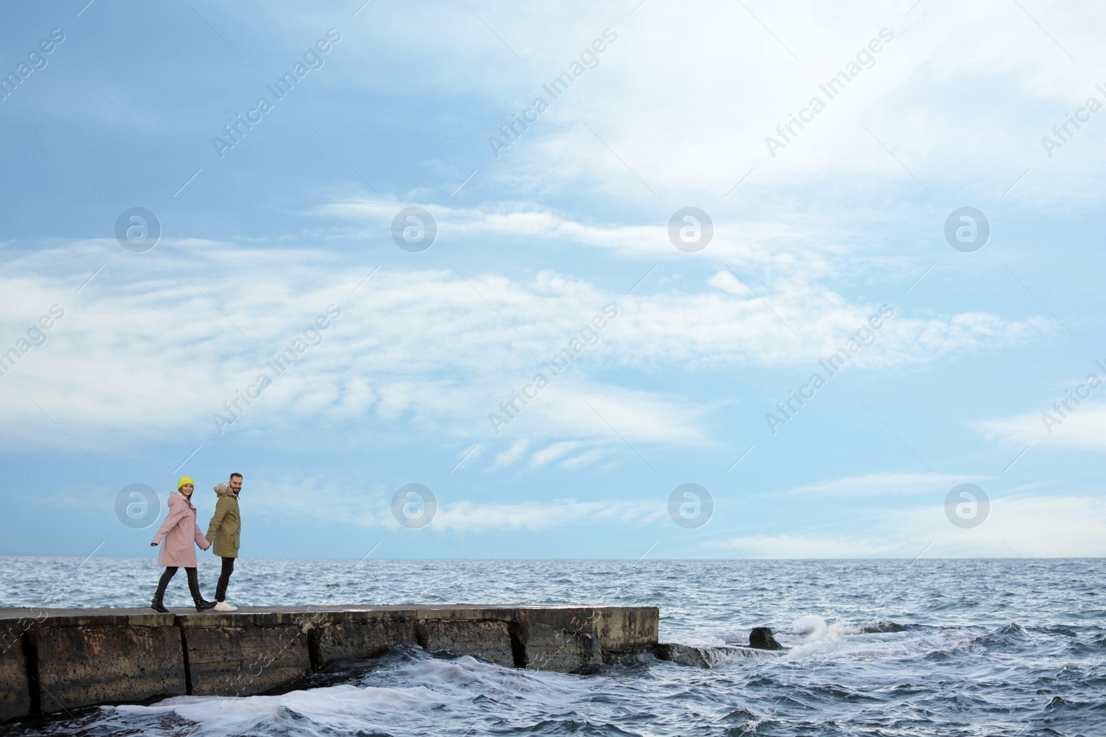 Photo of Lovely young couple walking on pier near sea
