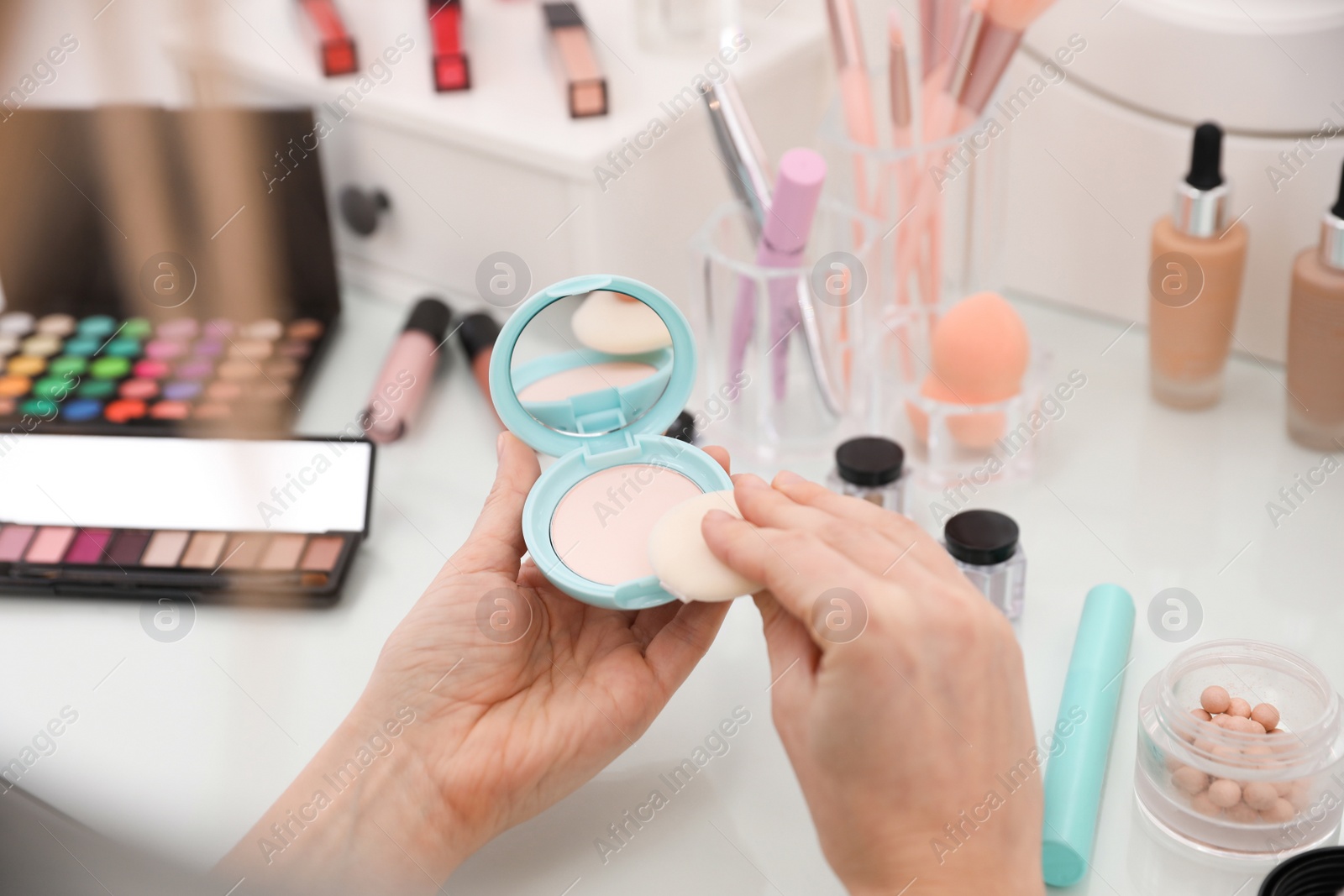 Photo of Woman applying makeup at dressing table, closeup