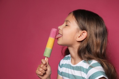 Cute little girl with delicious ice cream against color background, space for text