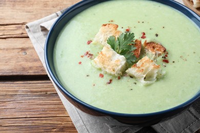 Photo of Delicious asparagus soup with croutons on wooden table, closeup