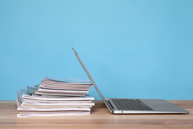 Photo of Laptop and stack of magazines on wooden table