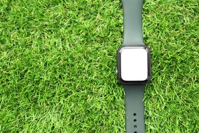 Photo of Stylish smart watch on green grass, top view. Space for text