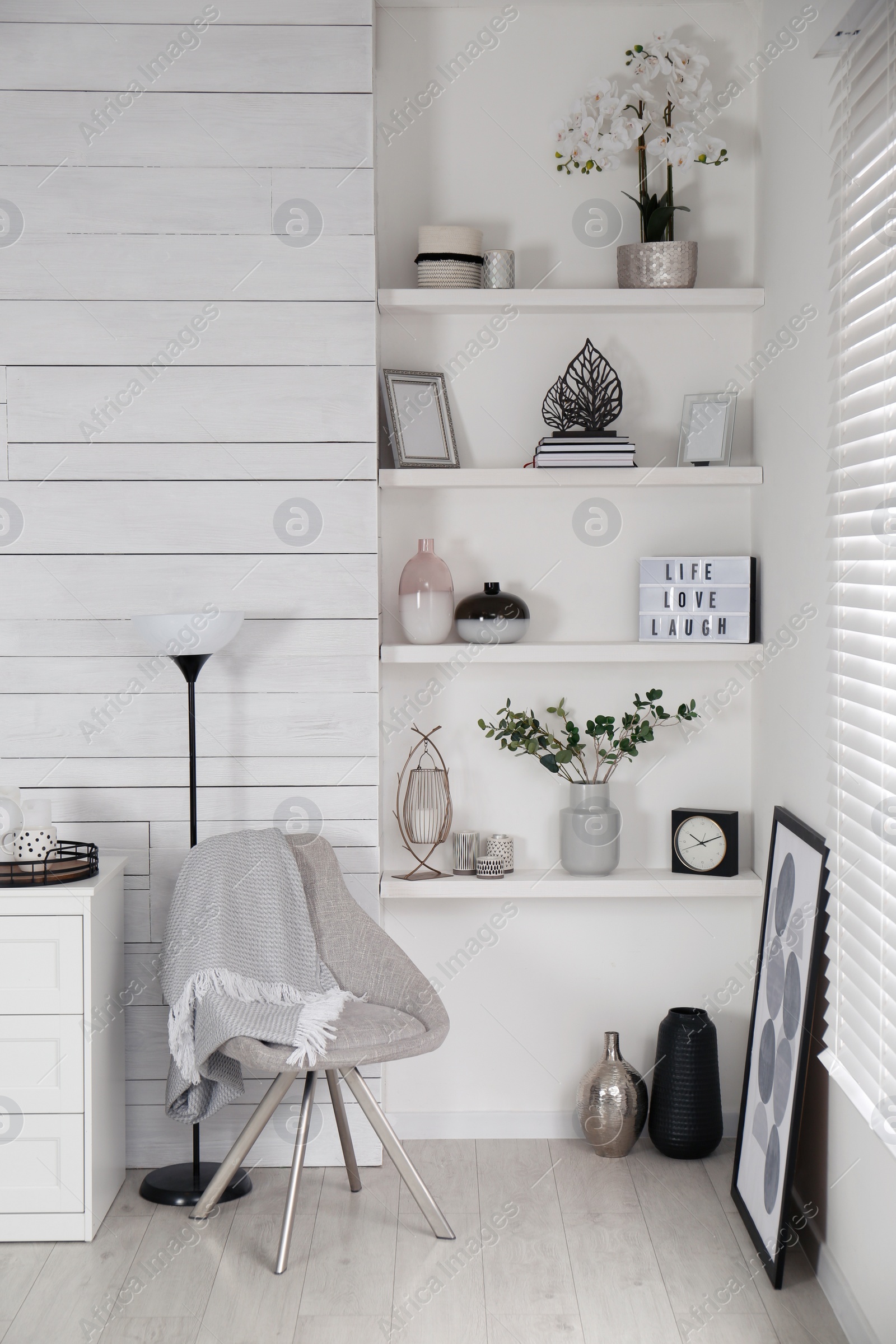 Photo of Cozy room interior with stylish furniture, wall shelves and beautiful decor elements