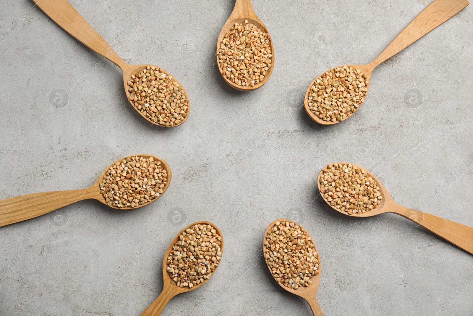 Photo of Frame made of uncooked green buckwheat grains in spoons on light table, flat lay. Space for text