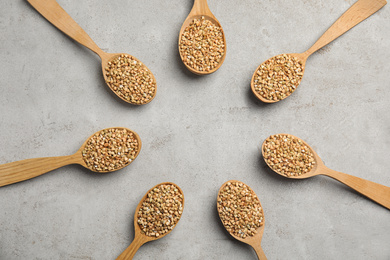 Photo of Frame made of uncooked green buckwheat grains in spoons on light table, flat lay. Space for text