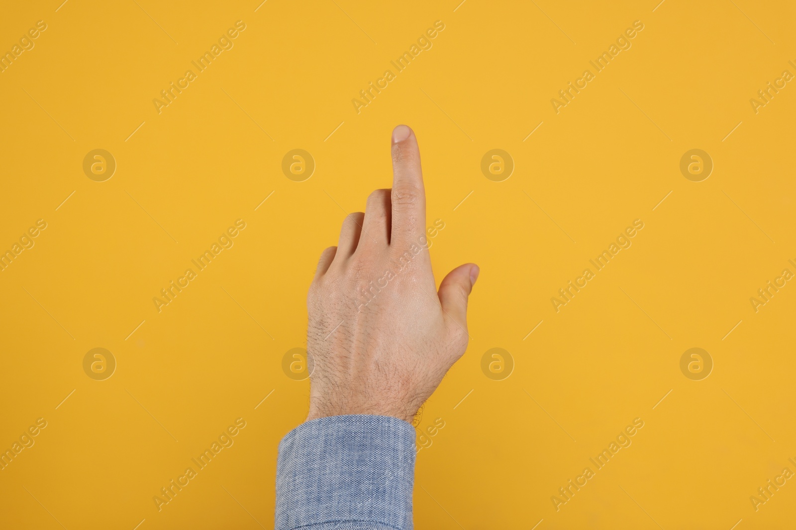Photo of Man pointing at something against yellow background, closeup on hand