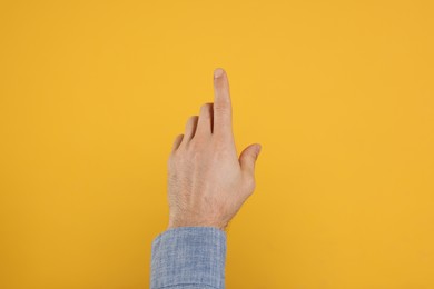 Man pointing at something against yellow background, closeup on hand