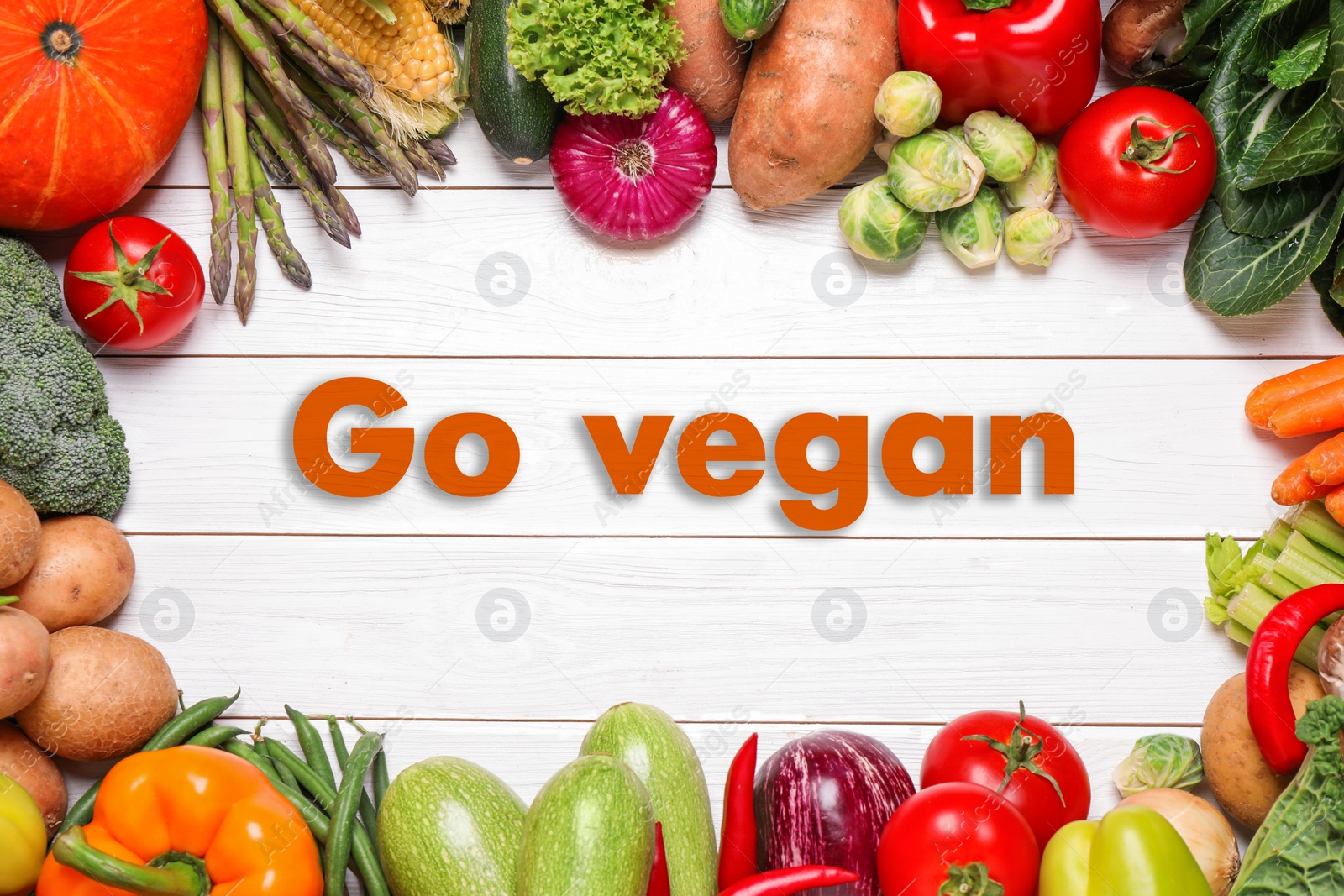 Image of Phrase Go Vegan and fresh vegetables on white wooden background, flat lay