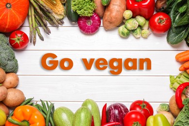 Image of Phrase Go Vegan and fresh vegetables on white wooden background, flat lay