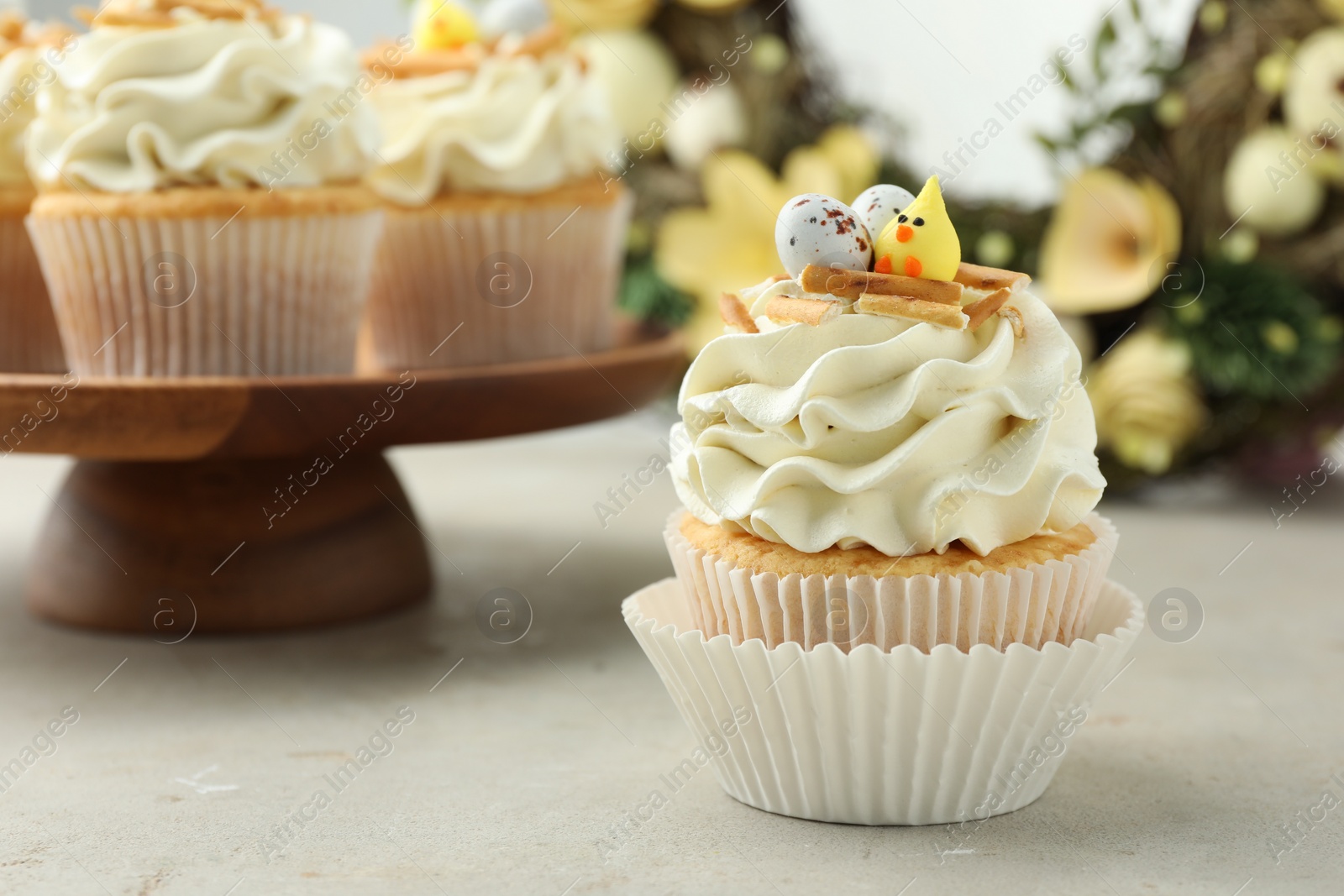 Photo of Tasty Easter cupcakes with vanilla cream on gray table