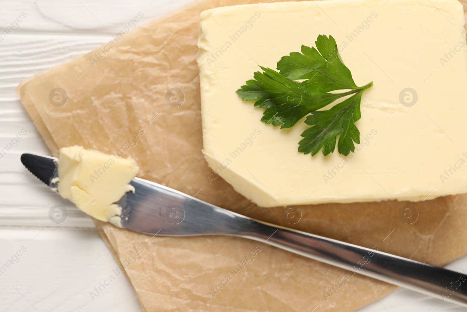 Photo of Tasty butter and knife on white wooden table, top view