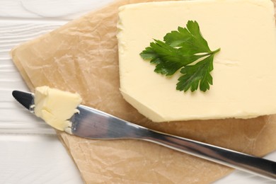 Photo of Tasty butter and knife on white wooden table, top view