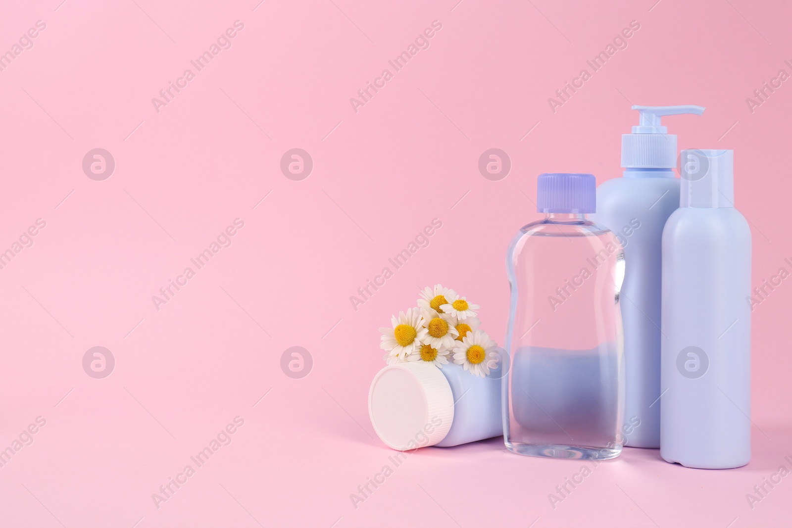 Photo of Different baby care products and chamomile flowers on pink background, space for text