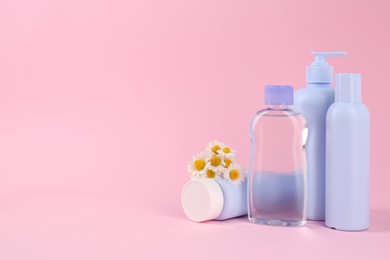 Photo of Different baby care products and chamomile flowers on pink background, space for text