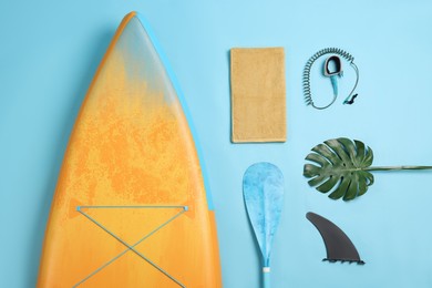 Flat lay composition with SUP board on light blue background. Water sport