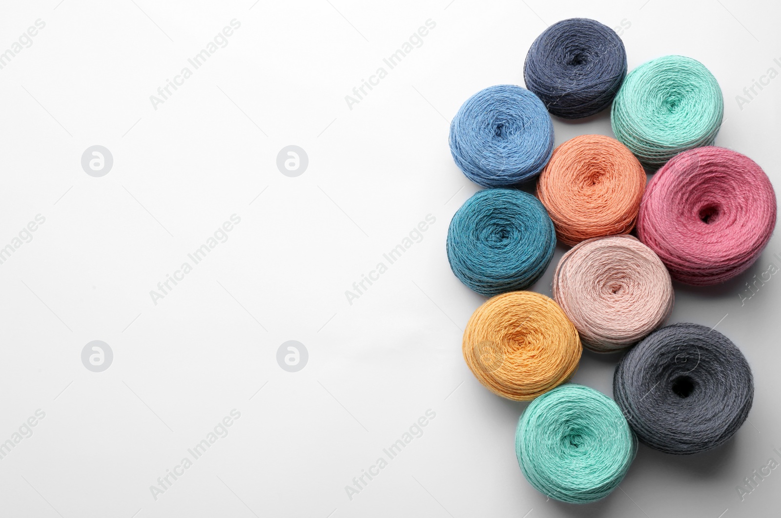 Photo of Clews of colorful knitting threads on white background, top view