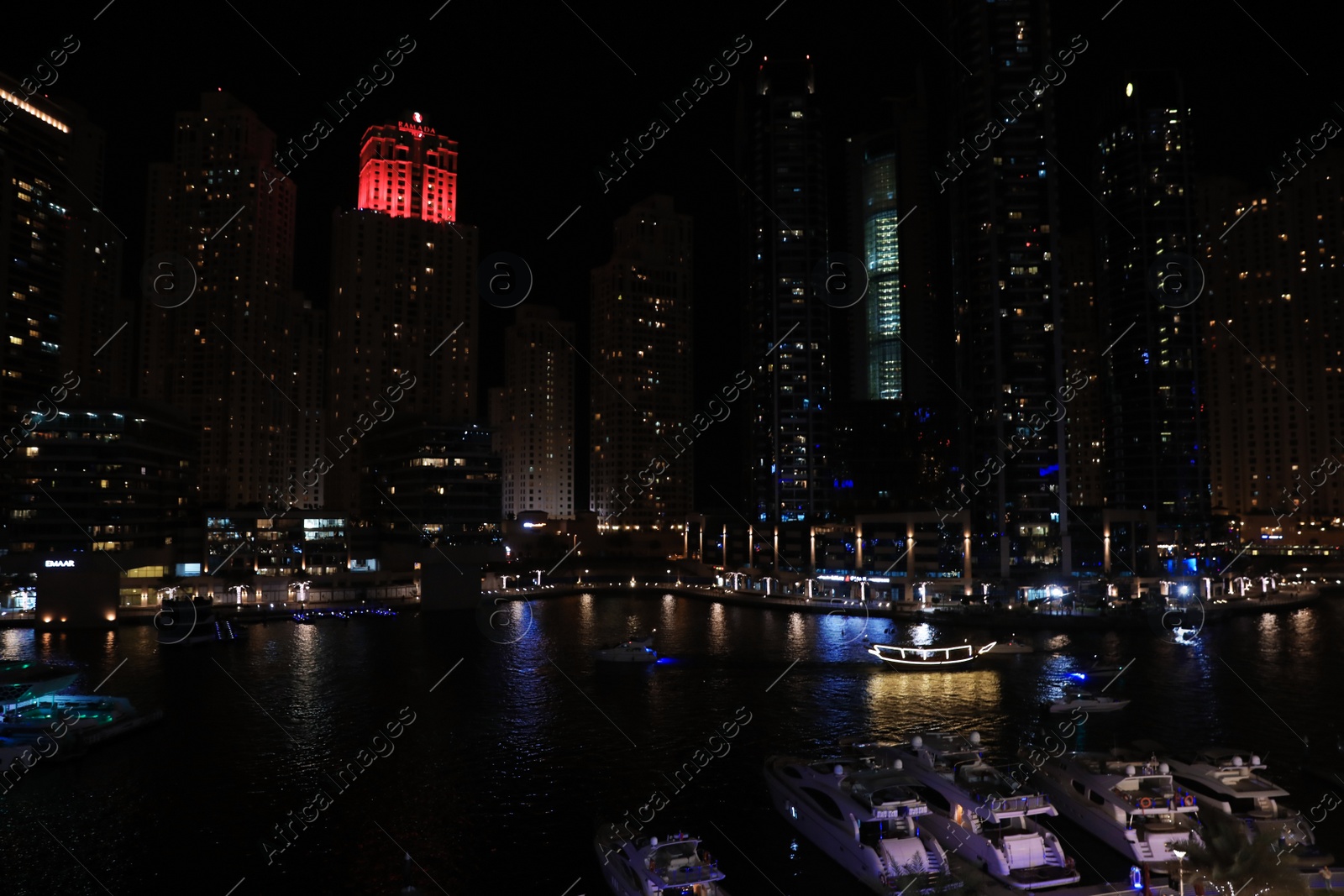 Photo of DUBAI, UNITED ARAB EMIRATES - NOVEMBER 03, 2018: Night cityscape of marina district with moored yachts and illuminated buildings