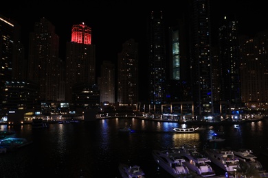 DUBAI, UNITED ARAB EMIRATES - NOVEMBER 03, 2018: Night cityscape of marina district with moored yachts and illuminated buildings