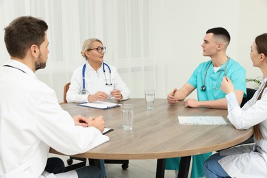 Photo of Medical conference. Teamdoctors having discussion at wooden table in clinic