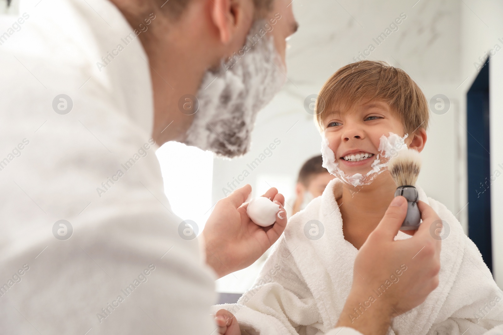 Photo of Dad applying shaving foam onto son's face in bathroom