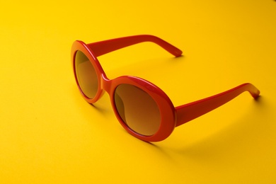 Photo of Stylish sunglasses on yellow background. Fashionable accessory