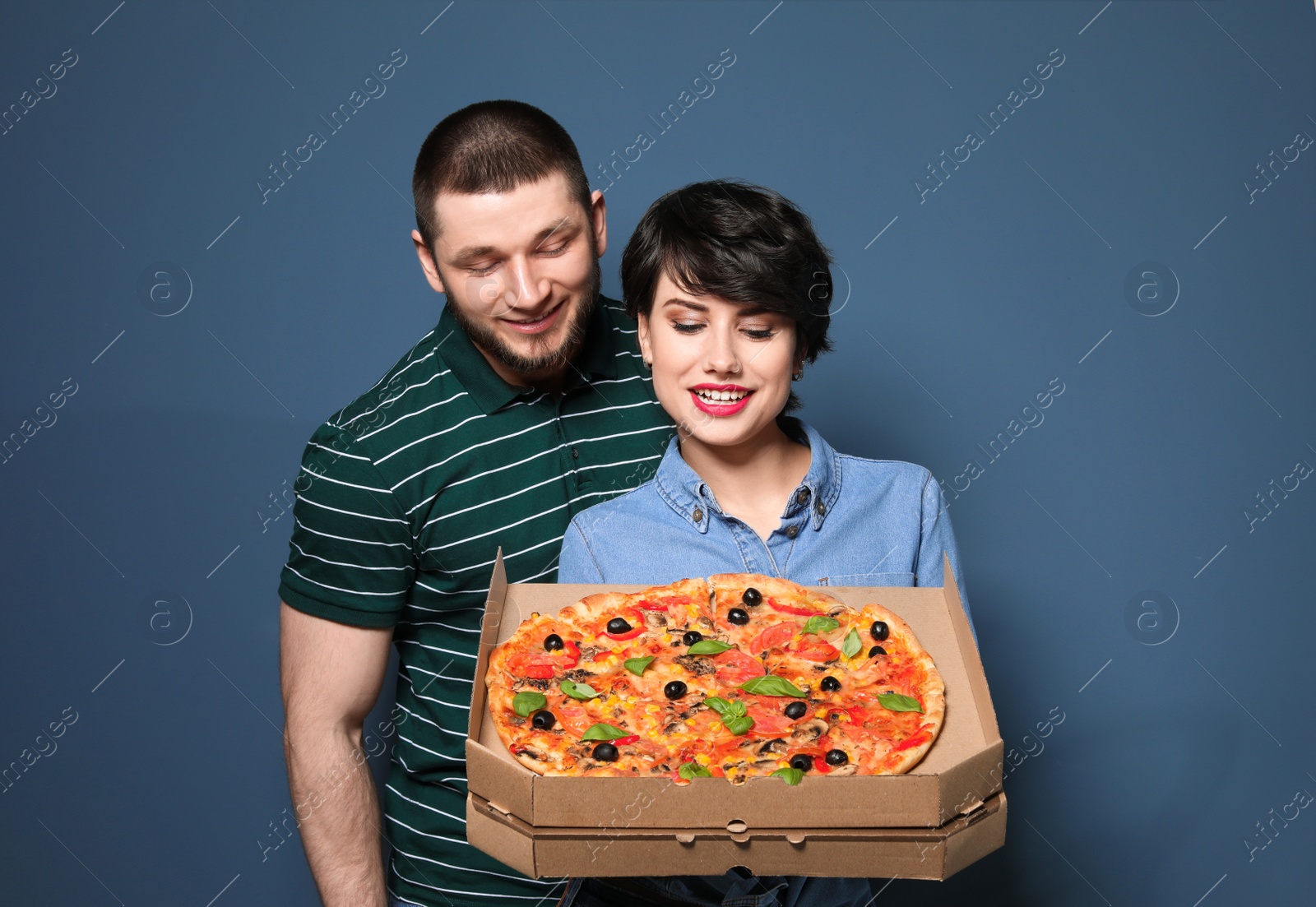 Photo of Attractive young couple with delicious pizza on color background