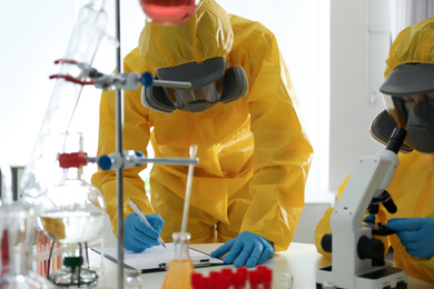 Scientists in chemical protective suits working at laboratory. Virus research