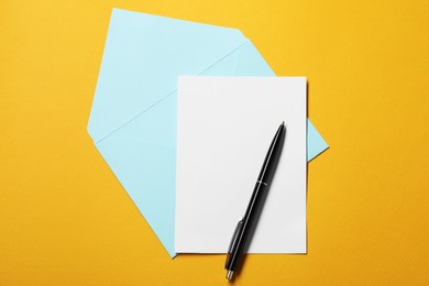 Photo of Blank sheet of paper, letter envelope and pen on orange background, top view