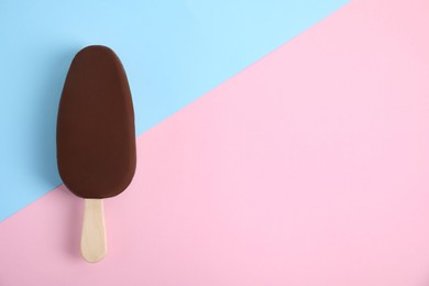 Photo of Ice cream glazed in chocolate on color background, top view. Space for text