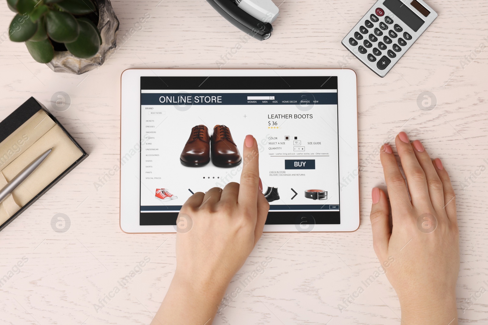 Photo of Woman with tablet shopping online at white wooden table, top view