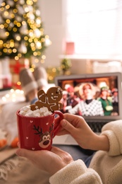 MYKOLAIV, UKRAINE - DECEMBER 25, 2020: Woman with sweet drink watching The Witches  movie on laptop at home, closeup. Cozy winter holidays atmosphere