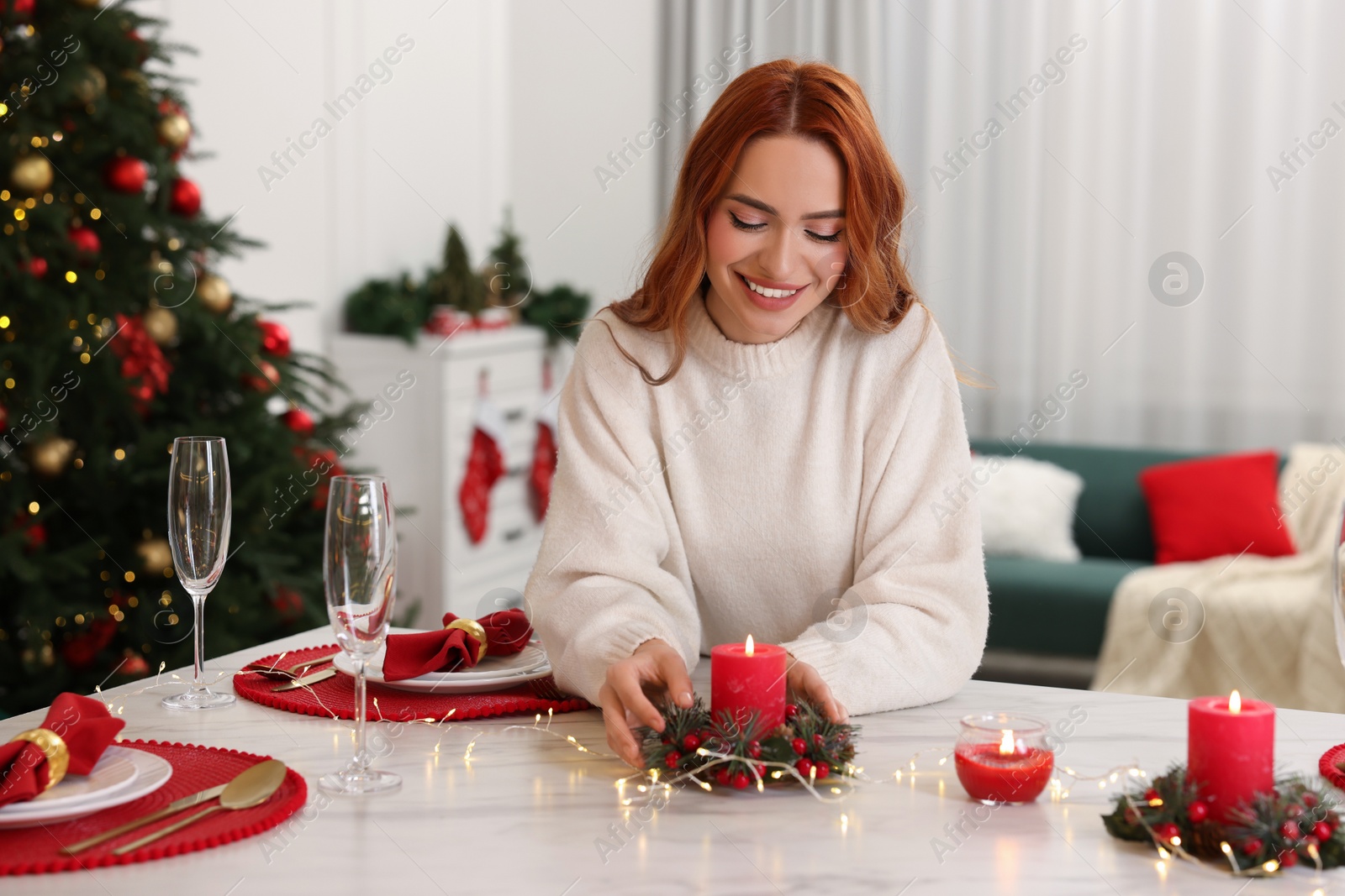 Photo of Beautiful young woman setting table in room decorated for Christmas