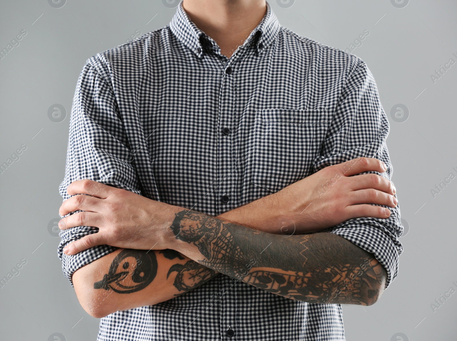 Photo of Young man with stylish tattoos on grey background