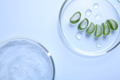 Photo of Cut aloe vera and cosmetic gel on light blue background, top view