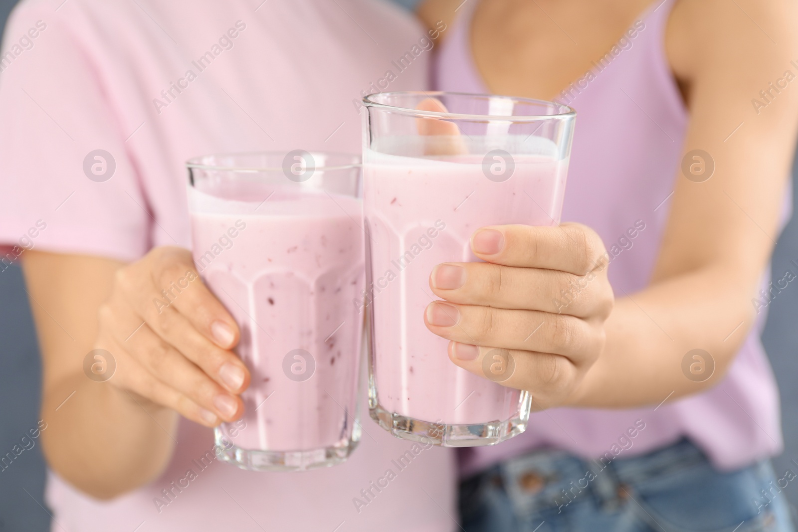 Photo of Women holding fig smoothie on grey background, closeup