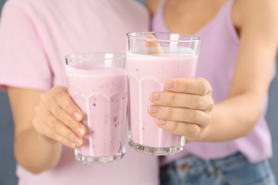 Women holding fig smoothie on grey background, closeup