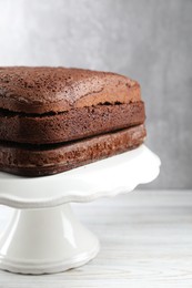 Stand with layers of homemade chocolate sponge cake on white wooden table