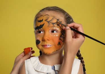 Photo of Artist painting face of little girl on orange background