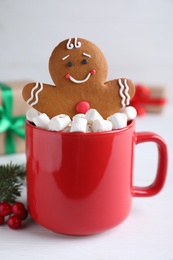 Photo of Gingerbread man in red cup with marshmallows on white table